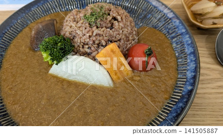一道時尚的咖啡館風格香料咖哩,上麵點綴著色彩繽紛的蔬菜。 一道時尚的咖啡館風格香料咖哩,上麵點綴著色彩繽紛的蔬菜。 141505887