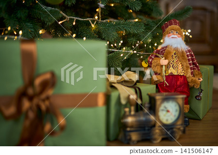 Santa Claus Figurine and Vintage Toy Train Near a Christmas Tree Santa Claus Figurine and Vintage Toy Train Near a Christmas Tree 141506147