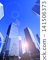 A cluster of skyscrapers and a cluster of high-rise office buildings bathed in sunlight. 141506373