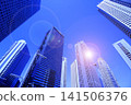 A cluster of skyscrapers and a cluster of high-rise office buildings bathed in sunlight. 141506376