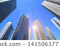 A cluster of skyscrapers and a cluster of high-rise office buildings bathed in sunlight. 141506377