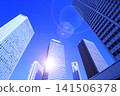 A cluster of skyscrapers and a cluster of high-rise office buildings bathed in sunlight. 141506378