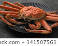A vibrant and luxurious snow crab served on a black plate. 141507561