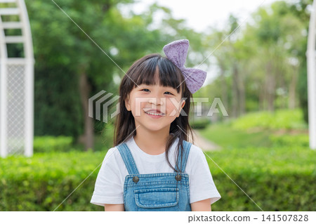 Asian little girl smiling in park, happy child portrait, outdoor lifestyle, childhood concept Asian little girl smiling in park, happy child portrait, outdoor lifestyle, childhood concept 141507828