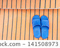 High angle view of blue rubber slippers on a wooden yacht deck with black caulking. This casual footwear represents summer relaxation, seaside vacation and nautical travel. Modern minimalist style. 141508973
