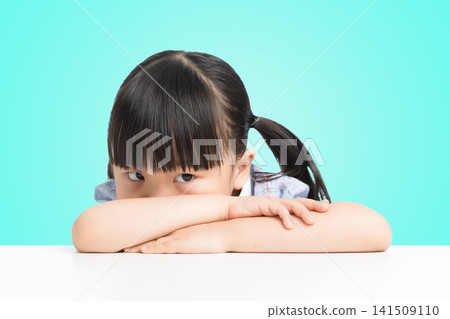 Pensive little girl leaning on arms looking away with green background Pensive little girl leaning on arms looking away with green background 141509110
