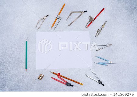 Drawing tools, various drawing compasses, supplies around white paper copy space. Top view of school desk. Drawing tools, various drawing compasses, supplies around white paper copy space. Top view of school desk. 141509279