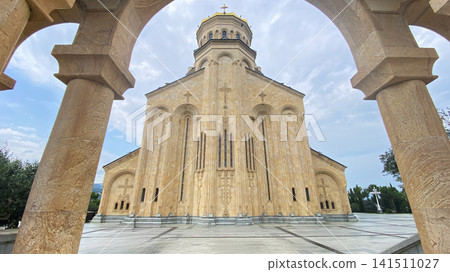 Sameba Cathedral rises above Tbilisi, framed by carved stone arches, presenting Georgian Orthodox architecture for pilgrimage tourism Sameba Cathedral rises above Tbilisi, framed by carved stone arches, presenting Georgian Orthodox architecture for pilgrimage tourism 141511027