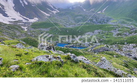 Blue Abudelauri Lake occupies a rocky hollow below snow-covered Chaukhi slopes in Georgia, revealing trail connections Blue Abudelauri Lake occupies a rocky hollow below snow-covered Chaukhi slopes in Georgia, revealing trail connections 141511055