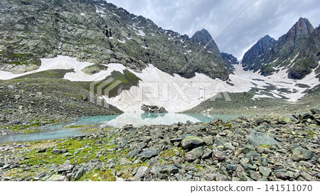White Abudelauri Lake rests beneath snowfields and jagged Chaukhi cliffs in Georgia, providing a visual for alpine habitat protection White Abudelauri Lake rests beneath snowfields and jagged Chaukhi cliffs in Georgia, providing a visual for alpine habitat protection 141511070