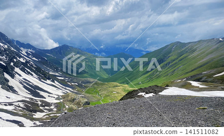 Juta Valley extends below Chaukhi Pass at 3300 meters in Georgia, revealing snowbound slopes and green highlands for destination branding Juta Valley extends below Chaukhi Pass at 3300 meters in Georgia, revealing snowbound slopes and green highlands for destination branding 141511082