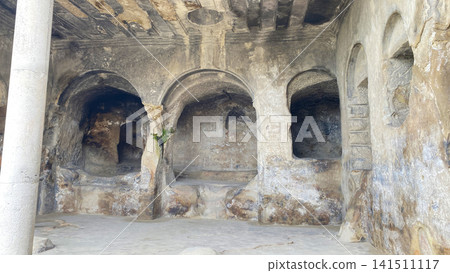 Ancient rock-cut hall inside Uplistsikhe features carved arches, columns, niches, and weathered stone surfaces in Georgia Ancient rock-cut hall inside Uplistsikhe features carved arches, columns, niches, and weathered stone surfaces in Georgia 141511117