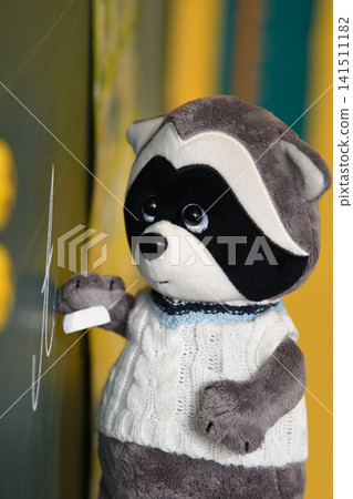 Cute Plush Raccoon Writing on Blackboard in Classroom. Cute Plush Raccoon Writing on Blackboard in Classroom. 141511182