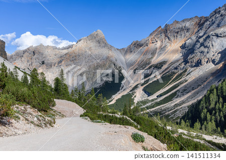Gravel trail entering the vast rocky basin of Piz de Sant Antone in the Fanes Dolomites Gravel trail entering the vast rocky basin of Piz de Sant Antone in the Fanes Dolomites 141511334