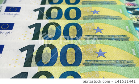 The 100 euro bills are stacked one on top of the other. Close-up. One hundred euros. The single currency of the European Union. European currency. Green background of money. The 100 euro bills are stacked one on top of the other. Close-up. One hundred euros. The single currency of the European Union. European currency. Green background of money. 141511441