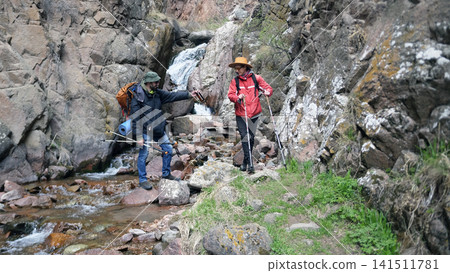 Two gay men are traveling in the mountains. A couple of friends are actively spending the weekend, they drink beer and enjoy the beauty of nature Two gay men are traveling in the mountains. A couple of friends are actively spending the weekend, they drink beer and enjoy the beauty of nature 141511781