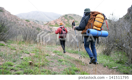 College students go hiking in the mountains, view from the back. Guys are walking on hills, mountains and ridges College students go hiking in the mountains, view from the back. Guys are walking on hills, mountains and ridges 141511795