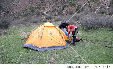 Camping life. Setting up a tent in a mountainous area. The wanderers travel the world together. Fresh air, freedom and tourism Camping life. Setting up a tent in a mountainous area. The wanderers travel the world together. Fresh air, freedom and tourism 141511817