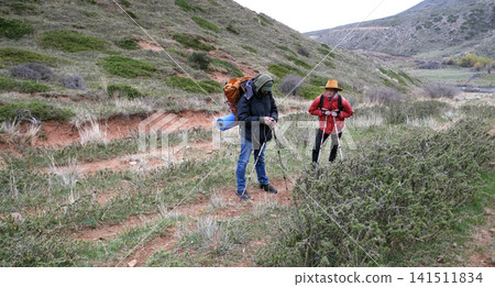 Two tired travelers stopped on the path to check the map. The guide took out his phone and checked the trail. Travelers walking Two tired travelers stopped on the path to check the map. The guide took out his phone and checked the trail. Travelers walking 141511834