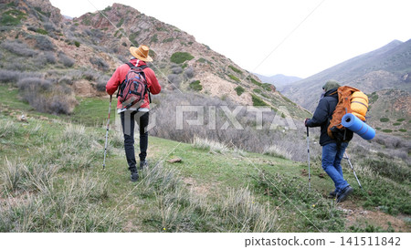 Two climbers climb the mountain, exploring a new route. A couple of friends are walking in the mountains. The guys travel together 141511842