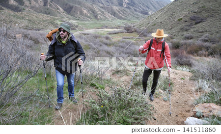 Two friends set off on a journey to a mountain peak. A trip in the mountains. Weekend camping trip. Trekking through hills Two friends set off on a journey to a mountain peak. A trip in the mountains. Weekend camping trip. Trekking through hills 141511860