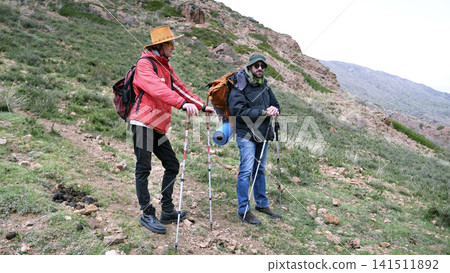 Two brothers are standing in the middle of a mountain trail and resting after a long trek. Travel through mountains, hills, ridges and clearings Two brothers are standing in the middle of a mountain trail and resting after a long trek. Travel through mountains, hills, ridges and clearings 141511892