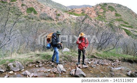 Two tourists have taken out their phones and are checking the map to see if they are following the route correctly. Weekend camping trip Two tourists have taken out their phones and are checking the map to see if they are following the route correctly. Weekend camping trip 141511907