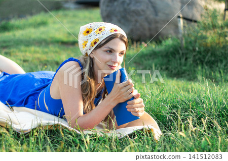 Girl sitting on grass with book. Summer reading ritual. Screen free zone. Intellectual growth through literature. Peaceful harmony between human and nature Girl sitting on grass with book. Summer reading ritual. Screen free zone. Intellectual growth through literature. Peaceful harmony between human and nature 141512083