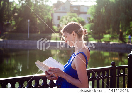 Woman reading in sunlit park. No smartphone. Cognitive refresh through pages. Self education in priority. Celebrating August 9 book lovers day Woman reading in sunlit park. No smartphone. Cognitive refresh through pages. Self education in priority. Celebrating August 9 book lovers day 141512098