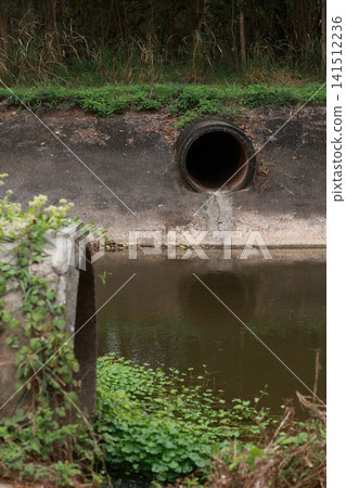 Concrete circular run-off pipe discharging water. sewage pipe polluting the river. Concrete circular run-off pipe discharging water. sewage pipe polluting the river. 141512236