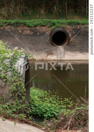 Concrete circular run-off pipe discharging water. sewage pipe polluting the river. Concrete circular run-off pipe discharging water. sewage pipe polluting the river. 141512237