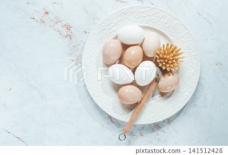 washed chicken eggs ,lying on a white plate, with a washing brush, lifestyle, no people, washed chicken eggs ,lying on a white plate, with a washing brush, lifestyle, no people, 141512428