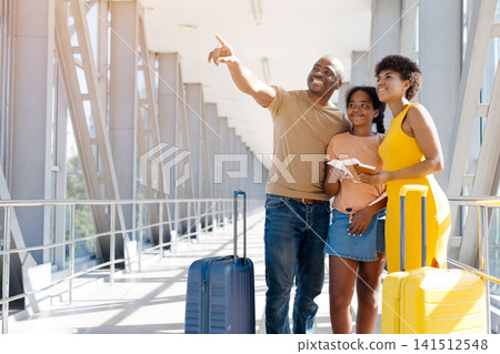 Black family of three at airport, father pointing upward at copy space Black family of three at airport, father pointing upward at copy space 141512548