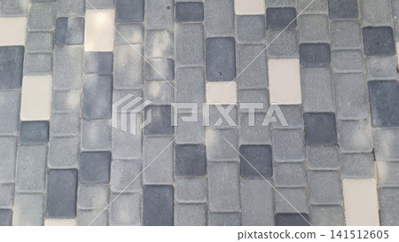 Overhead view of a grid patterned floor with light gray, dark gray, and off white rectangular tiles creating a subtle variegated texture. Overhead view of a grid patterned floor with light gray, dark gray, and off white rectangular tiles creating a subtle variegated texture. 141512605