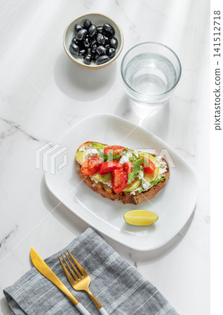 Avocado toast with cream cheese, feta, tomato and arugula on a marble background Avocado toast with cream cheese, feta, tomato and arugula on a marble background 141512718