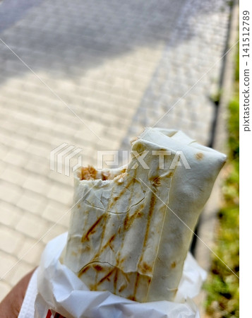 Enjoying a Tasty Kebab While Strolling Along a Lively Cobblestone Street Enjoying a Tasty Kebab While Strolling Along a Lively Cobblestone Street 141512789