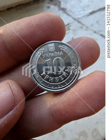 Ukrainian Ten Hryvnia Coin Held in Fingers Showcasing Detailed Design Ukrainian Ten Hryvnia Coin Held in Fingers Showcasing Detailed Design 141512798