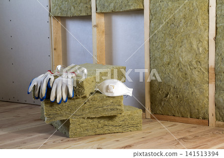 Rock wool and fiberglass insulation staff material for cold barrier. Tools for work with glass wool: protective goggles, glasses and mask. Warm home, economy, construction and renovation concept. Rock wool and fiberglass insulation staff material for cold barrier. Tools for work with glass wool: protective goggles, glasses and mask. Warm home, economy, construction and renovation concept. 141513394