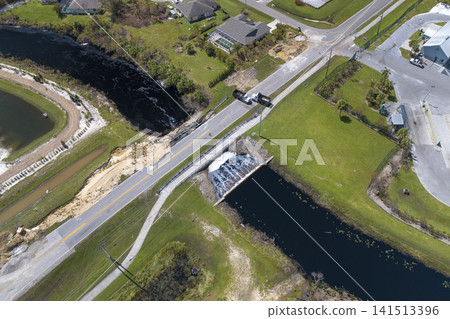 Roadblock at damaged road bridge destroyed by river after flood water washed away asphalt. Rebuilding of ruined transportation infrastructure Roadblock at damaged road bridge destroyed by river after flood water washed away asphalt. Rebuilding of ruined transportation infrastructure 141513396