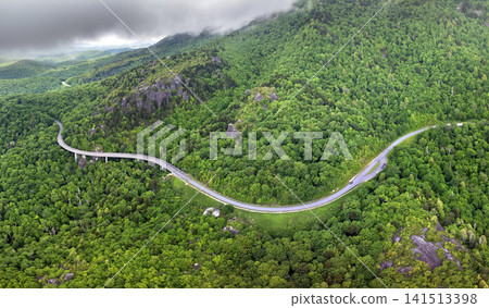 Road trip driving on Linn Cove Viaduct in Appalachian mountains. Winding parkway in mountain forest with green canopies in summer rain season Road trip driving on Linn Cove Viaduct in Appalachian mountains. Winding parkway in mountain forest with green canopies in summer rain season 141513398