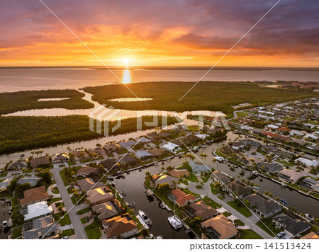 Punta Gorda, Florida at evening hour. Waterfront suburban houses and palm trees shine in warm tropical sunset atmosphere. Punta Gorda, Florida at evening hour. Waterfront suburban houses and palm trees shine in warm tropical sunset atmosphere. 141513424