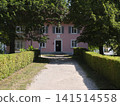 House with a pathway surrounded by trees and bushes in bright daylight 141514558
