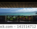 A breathtaking view of the sea unfolds beyond the wooden frame of the gazebo. 141514712
