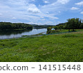 A tranquil lakeside landscape surrounded by summer skies and green forests. 141515448