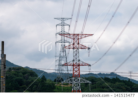 山區中架設的輸電塔和高壓輸電線路的景觀。 山區中架設的輸電塔和高壓輸電線路的景觀。 141515477