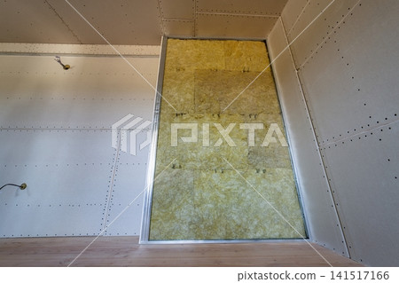 Wall of a room under renovation with mineral rock wool insulation and metal frame prepared for drywall plates. Wall of a room under renovation with mineral rock wool insulation and metal frame prepared for drywall plates. 141517166