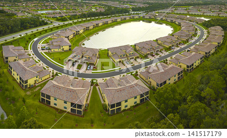 View from above of densely built residential houses near retention ponds in closed living clubs in south Florida. American dream homes as example of real estate development in US suburbs View from above of densely built residential houses near retention ponds in closed living clubs in south Florida. American dream homes as example of real estate development in US suburbs 141517179
