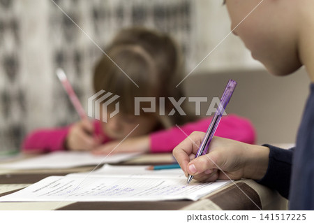 Two cute young children, boy and girl, brother and sister doing homework, writing and drawing at home on blurred background. Art education, creativity and children activities concept. Two cute young children, boy and girl, brother and sister doing homework, writing and drawing at home on blurred background. Art education, creativity and children activities concept. 141517225