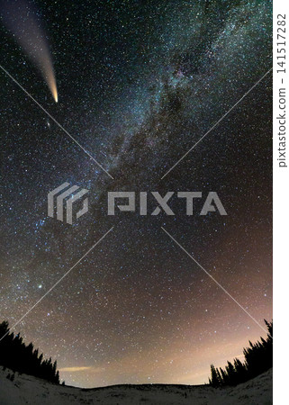 Surreal view of night in mountains with starry dark blue cloudy sky and C/2020 F3 (NEOWISE) comet with light tail. 141517282