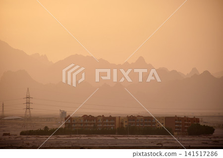 Sunset landscape with remote hotel complex against dark mountain peaks in egyptian desert Sunset landscape with remote hotel complex against dark mountain peaks in egyptian desert 141517286